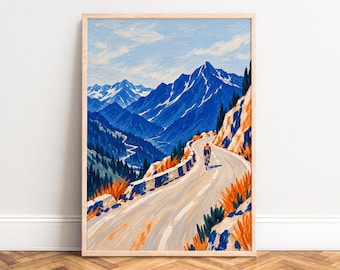 May include: A framed art print depicting a cyclist in an orange jersey riding along a winding mountain road. The scene features deep blue peaks with snow-capped summits, rocky cliffs, and vibrant orange foliage under a light blue sky.