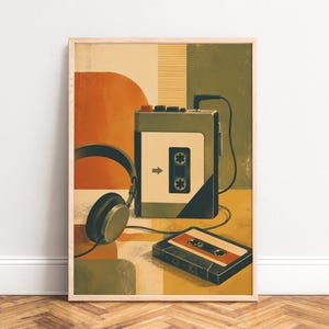 May include: A framed wall art print featuring a portable cassette player in olive green with a white cassette tape inserted. A pair of black over-ear headphones is connected to the player, and a separate orange and white cassette tape lies below.
