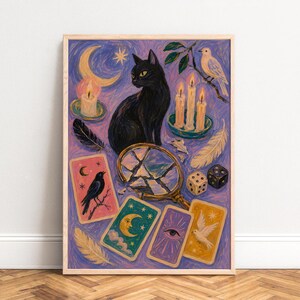 Könnte beinhalten: Ein rechteckiger Kunstdruck in einem hellen Holzrahmen mit einem Gemälde einer schwarzen Katze, einem zerbrochenen Handspiegel, vier Tarotkarten, drei brennenden Kerzen, zwei Würfeln, Federn und einem Vogel auf einem Ast vor einem violetten Hintergrund mit Mondsichel.