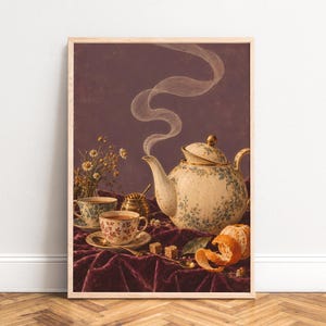 Peut inclure: Une impression d'art encadrée représentant une théière crème à motifs floraux bleus, deux tasses assorties, un petit pot à miel, des morceaux de sucre et une orange pelée sur un tissu en velours violet foncé sur fond sombre.