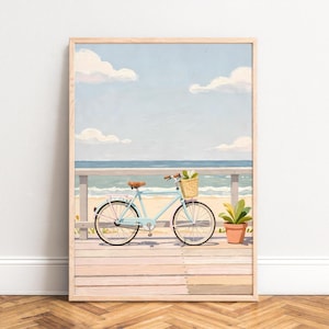 Può includere: Una stampa artistica incorniciata raffigura una bicicletta azzurra con un cestino di vimini su una passerella di legno. La scena comprende una spiaggia, l'oceano e un cielo con nuvole. È presente anche una pianta in vaso. L'opera d'arte è in una cornice di legno.