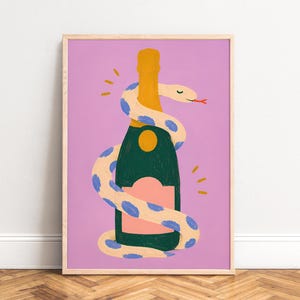 Op de afbeelding: Een ingelijste kunstprint met een champagnefles omwikkeld door een grillige slang. De fles is donkergroen met een gouden dop en een roze etiket. De slang is crèmekleurig met blauwe stippen, tegen een lavendel achtergrond.
