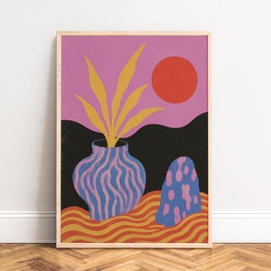 May include: A framed art print featuring a stylized landscape with a pink sky and a red sun. A blue vase with wavy purple stripes holds yellow leaves. Beside it sits a blue rock with pink spots on a wavy orange and yellow ground with black hills.