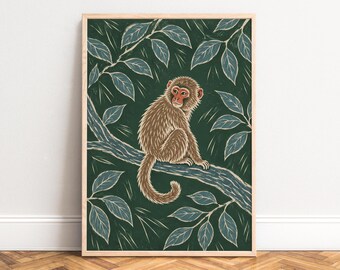 May include: A framed art print featuring a brown monkey with a red face sitting on a tree branch. The background is a deep forest green with stylized blue-grey leaves and thin white lines, all enclosed in a light-colored wooden frame.