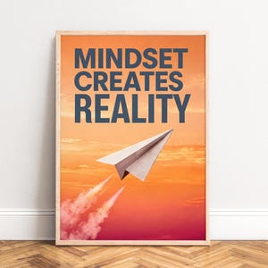 Könnte beinhalten: Ein gerahmter Kunstdruck mit einem Papierflieger, der durch einen orangefarbenen und roten Sonnenuntergangshimmel fliegt. Der Text MINDSET CREATES REALITY ist in großen dunkelblauen Großbuchstaben über dem Papierflieger abgebildet.