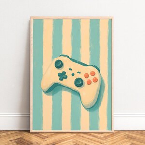 Peut inclure: Une impression d'art mural encadrée représentant une manette de jeu vidéo couleur crème avec des boutons bleu sarcelle foncé et orange. La manette est centrée sur un fond de rayures verticales peintes à la main en alternance sarcelle et crème.