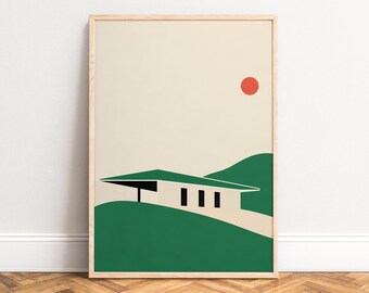 May include: A framed wall art print featuring a flat graphic illustration of a house with a flat roof set against green rolling hills and a beige sky with a single solid red circle representing the sun positioned in the upper right corner.