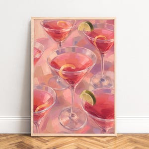May include: A framed art print featuring an oil painting style illustration of multiple martini glasses filled with a pink cocktail. Each glass is garnished with a thin citrus peel or a lime wedge, set against a textured, abstract pink background.