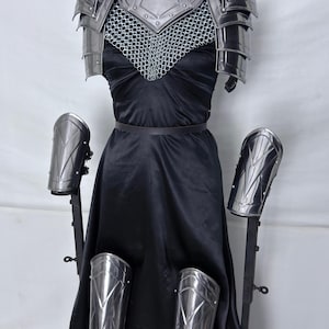 May include: A complete set of steel battle armor, including a chest plate, shoulder guards, chainmail, and arm and leg protection. The armor is displayed on a mannequin with a black dress. The Steel Heritage logo is visible.