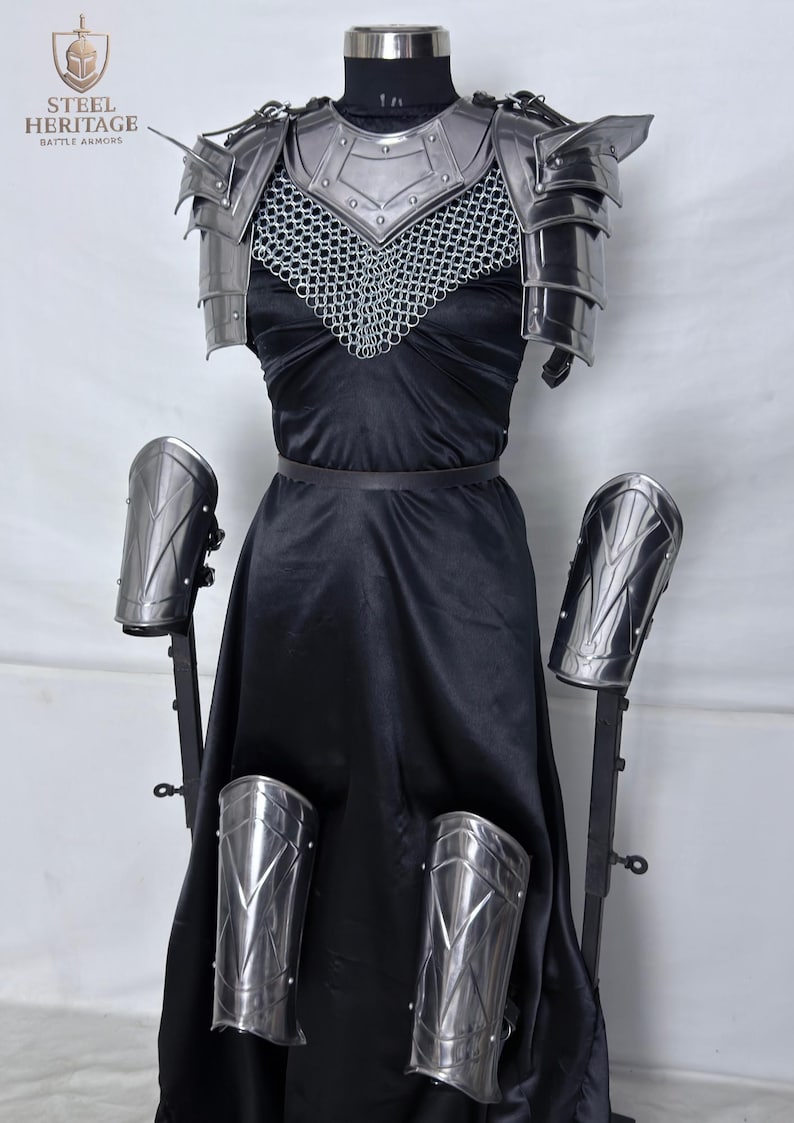 May include: A complete set of steel battle armor, including a chest plate, shoulder guards, chainmail, and arm and leg protection. The armor is displayed on a mannequin with a black dress. The Steel Heritage logo is visible.