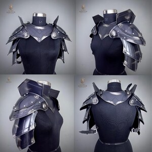 May include: Black steel shoulder armor with layered plates and rivet details. The armor is displayed on a black mannequin, showcasing its design and craftsmanship. The armor features a neck guard and shoulder spikes.