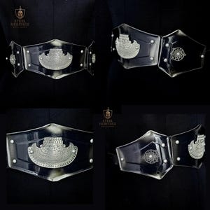 May include: Black and silver belt with decorative metal accents. The belt features a central silver emblem and smaller circular designs. The Steel Heritage logo is visible in the upper left corner.