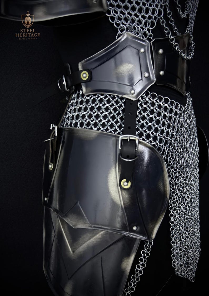 May include: Close-up of medieval armor, featuring a combination of polished metal plates and chainmail. The armor includes a breastplate, shoulder guards, and leg protection, all secured with leather straps and buckles. The Steel Heritage logo is visible.