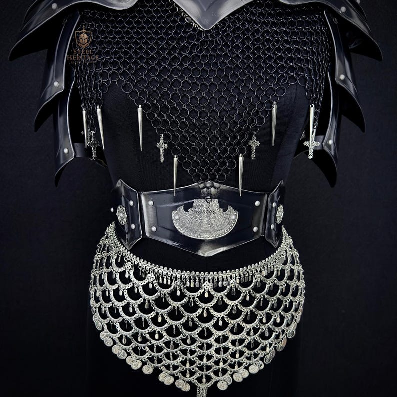 May include: Black medieval armor set featuring a chainmail shirt, shoulder pauldrons, and a studded belt with a decorative buckle. The armor is adorned with silver crosses and pendants, and a silver chainmail skirt.