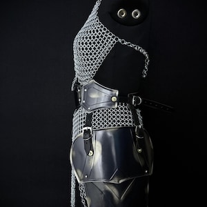 May include: A medieval-style battle armor set displayed on a black mannequin. The armor includes a chainmail top, a black leather belt with a metal buckle, and black metal chest and hip plates. The Steel Heritage Battle Armors logo is visible.