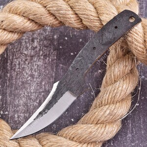 May include: A custom knife blade blank featuring a dark, textured finish on the handle area and a polished, sharp edge. The handle section includes three small circular holes and one larger hole at the end. The text EPIKUT CUSTOM KNIVES is visible.