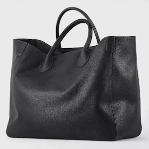 May include: A large black tote bag with a textured, pebbled surface. The bag features two rounded top handles attached to the main body with reinforced stitching. The design includes a wide, open-top opening and a structured, rectangular base.