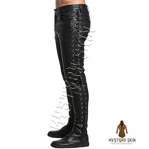May include: Black leather trousers featuring lace-up detailing on the sides. The trousers are fitted and have a classic five-pocket design. The image also shows black boots. The text "MYSTERY SKIN" is visible in the bottom right corner.