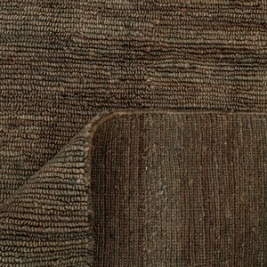 May include: Close-up of a brown woven rug with a textured surface. The rug is folded over, revealing the underside with a different weave pattern. The colour is a dark, earthy brown.