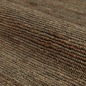 May include: Close-up of a textured, woven rug. The rug features a natural colour palette with shades of brown and tan. The fibres are tightly woven, creating a durable and visually appealing surface. The rug's texture adds warmth and a rustic feel to any space.