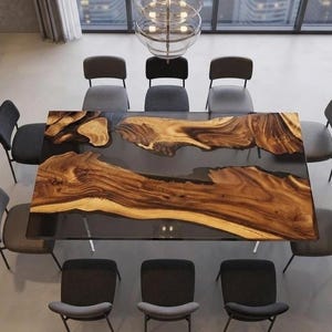 Könnte beinhalten: Ein rechteckiger Esstisch mit einer Massivholzplatte mit natürlicher Baumkante und ausgeprägter Maserung, die in eine dunkle, halbtransparente Harzoberfläche eingelassen ist, auf Metallbeinen und umgeben von zehn grauen Polsterstühlen.