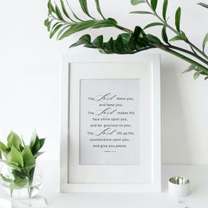 Könnte beinhalten: Ein weiß gerahmter Druck mit dem Text "The Lord bless you, and keep you; The Lord makes His face shine upon you, and be gracious to you; The Lord lift up His countenance upon you, and give you peace."