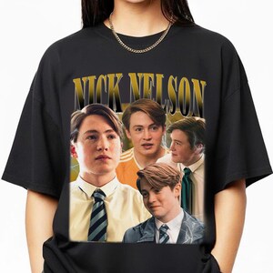 Puede incluir: Camiseta negra con un collage de imágenes de una persona y el texto "NICK NELSON" en dorado. Las imágenes muestran a la persona con diferentes atuendos, incluyendo camisa y corbata, en un estilo vintage.