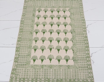 Op de afbeelding: Rechthoekig beige tapijt met een groen bloemmotief en franjes. Het tapijt heeft een centraal veld van groene waaiervormige ontwerpen op een beige achtergrond, omlijst door een groene rand met geometrische patronen. De randen hebben franjes.