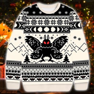 Könnte beinhalten: Cremefarbener Pullover mit einem schwarz-weißen Pixelmuster. Der Pullover zeigt eine große schwarze Motte mit roten Augen, Schneeflocken sowie Berg- und Baummotiven. Das Design umfasst Mondphasen und geometrische Muster.