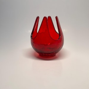 May include: A vibrant red glass bowl with a textured surface. The bowl has a unique, open design with four upward-curving points, resembling a stylized flower or crown. The bowl is a striking decorative piece.