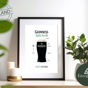 May include: A framed print featuring a diagram of a pint of Guinness stout. The print includes the Guinness logo and the text "Split the G" and "Irish Guide." The print is in a black frame and is displayed on a white surface.