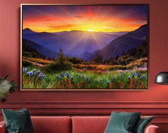 May include: A living room with a red sofa, teal pillows, and a framed landscape painting. The painting depicts a sunset over mountains with a vibrant sky. A large potted plant and a modern floor lamp complete the scene.