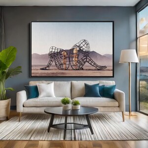 May include: A living room scene featuring a large framed artwork depicting two wireframe figures in a seated position. The room includes a beige sofa with blue and white pillows, a round black coffee table, and a floor lamp.
