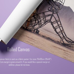 May include: Rolled canvas print featuring a wire sculpture of a seated figure against a landscape backdrop. The canvas is partially rolled, revealing its white interior. The text "Rolled Canvas" is visible, along with additional details.