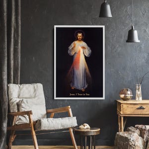 May include: A framed print of a religious figure with a halo, wearing white and light blue robes, with red and white light emanating from the chest. The text "Jesus, I Trust in You" is at the bottom.