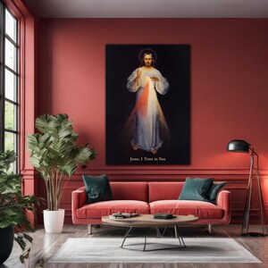 May include: A framed religious artwork depicting Jesus with light emanating from his chest. The artwork is set against a black background and features the text "Jesus, I Trust in You". The image is displayed in a living room setting.