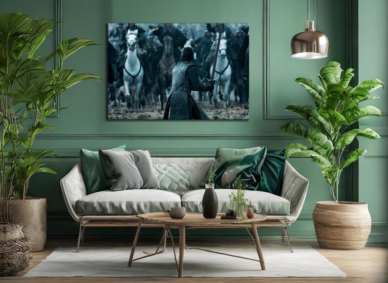 May include: A framed canvas print depicting a battle scene with riders on horseback. The artwork features a central figure facing a charge of horses, with a muted color palette of blues, grays, and whites. The print is displayed above a modern sofa.