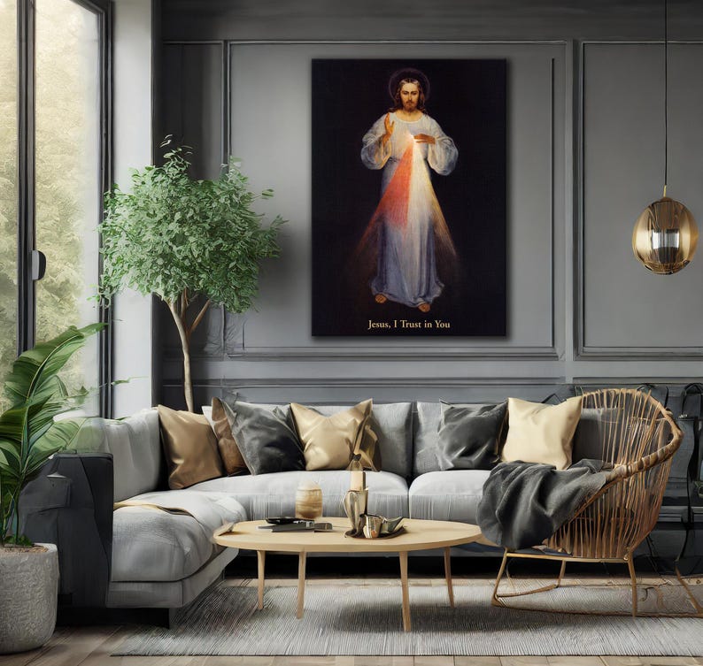 May include: A framed canvas print of Jesus with a halo, wearing a white robe, with red and white light emanating from his chest. The text "Jesus, I Trust in You" is at the bottom. The print hangs above a gray sofa in a living room.