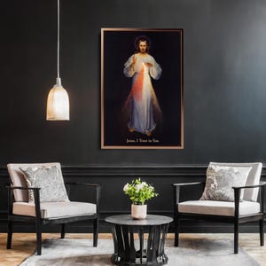 May include: A framed religious artwork depicting a figure in white robes with red and blue light emanating from the chest. The text "Jesus, I Trust in You" is at the bottom. The artwork hangs on a dark wall above two armchairs.