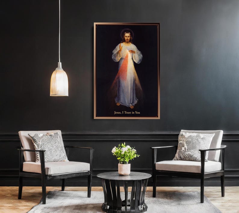 May include: A framed religious artwork depicting a figure in white robes with red and blue light emanating from the chest. The text "Jesus, I Trust in You" is at the bottom. The artwork hangs on a dark wall above two armchairs.