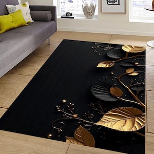 Könnte beinhalten: Ein rechteckiger schwarzer Teppich mit einem goldenen und schwarzen Blattdesign. Der Teppich hat große, stilisierte Blätter in Gold und Schwarz mit goldenen Akzenten auf dunklem Hintergrund. Der Teppich liegt auf einem Holzboden.