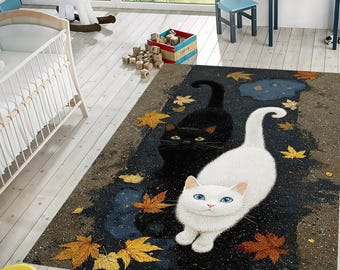 Puede incluir: Alfombra rectangular con diseño de gatos. Un gato es blanco con ojos azules, el otro es negro. La alfombra tiene un fondo oscuro con hojas de otoño.