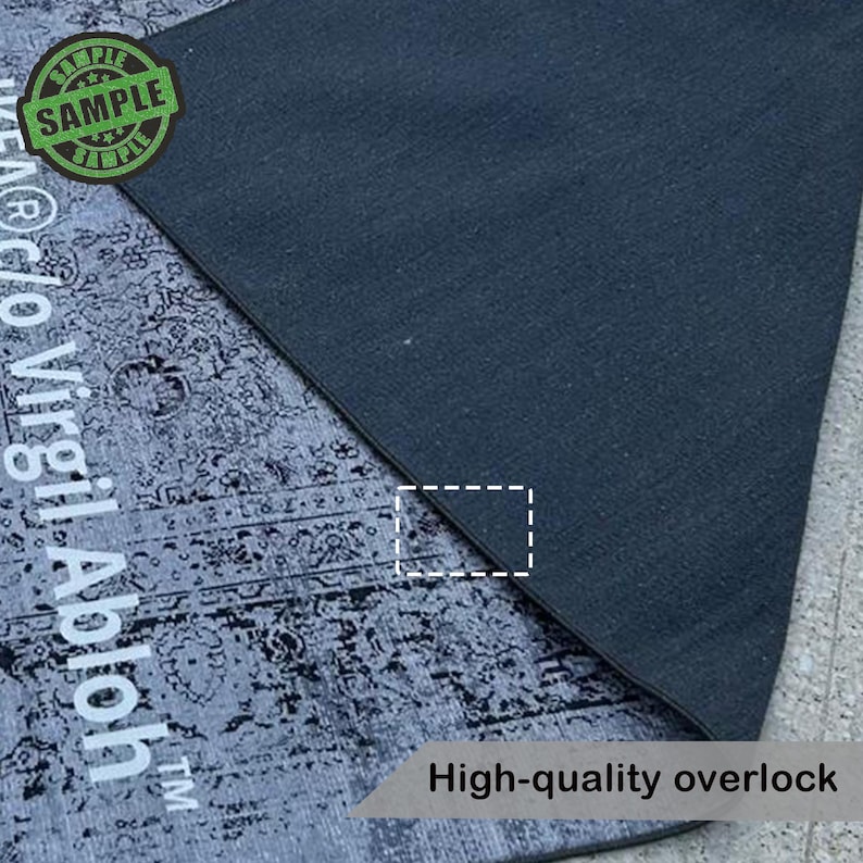 Puede incluir: Una secci&oacute;n de una alfombra gris y negra estampada con un borde de sobrehilado gris oscuro. La alfombra tiene un aspecto envejecido y vintage. El texto "SAMPLE" est&aacute; en un c&iacute;rculo verde. El texto "High-quality overlock" es visible.