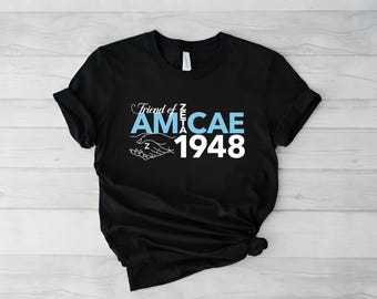 Op de afbeelding: Zwart T-shirt met de tekst "Friend of Zeta Amicae 1948" in wit en lichtblauw. Het ontwerp bevat een handdrukgrafiek. Het shirt is gemaakt van een zacht materiaal en is geschikt voor casual wear.
