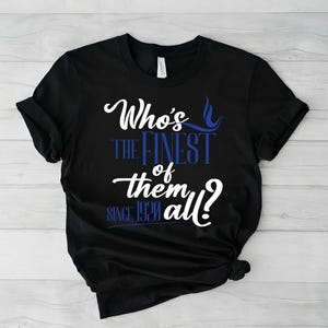 May include: A black short-sleeve t-shirt featuring white and blue text that reads Who's the Finest of them all? since 1920. The design uses a mix of cursive and block lettering, with a small blue flame graphic positioned above the word Finest.