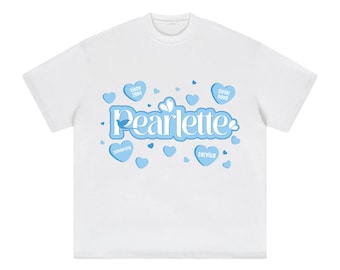 Op de afbeelding: Wit t-shirt met het woord "Pearlette" in lichtblauwe, cursieve letters. Het ontwerp bevat lichtblauwe harten met de tekst "since 1964", "sister hood", "scholarship" en "service".