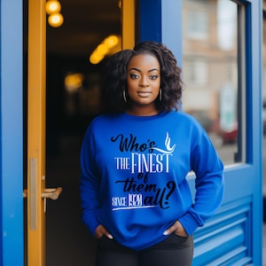 May include: A bright blue long-sleeve sweatshirt featuring black and white text that reads Who's THE FINEST of them all? SINCE 1920. The garment has a crew neckline and a relaxed fit, with the graphic centered prominently on the front chest area.