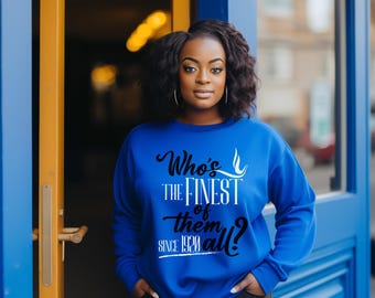 Op de afbeelding: Een felblauw sweatshirt met lange mouwen en zwarte en witte tekst die luidt Who's THE FINEST of them all? SINCE 1920. Het kledingstuk heeft een ronde hals en een relaxte pasvorm, met de afbeelding gecentreerd op de voorzijde van de borst.