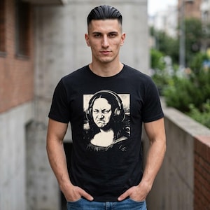 Könnte beinhalten: Ein schwarzes Kurzarm-T-Shirt mit einem Grafikdruck der Mona Lisa, die große Over-Ear-Kopfhörer trägt. Das Kunstwerk ist in einem monochromen Stil mit quadratischem Rahmen gehalten und mittig auf der Brust platziert.
