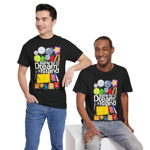May include: Black t-shirts with a colorful graphic design featuring cartoon characters and the text "Battle for Dream Island." The design includes various shapes and colors, with a playful and animated style. The shirts are worn by two people.